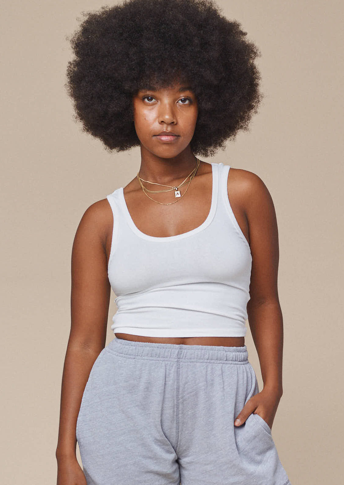 A woman wearing a cropped, fitted scoop neck tank top in white.