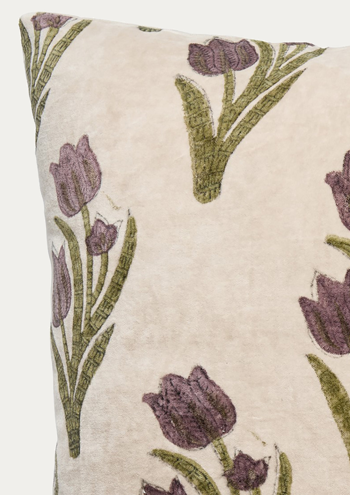 Close-up of a decorative throw pillow featuring a muted purple tulip pattern on a warm cream background.