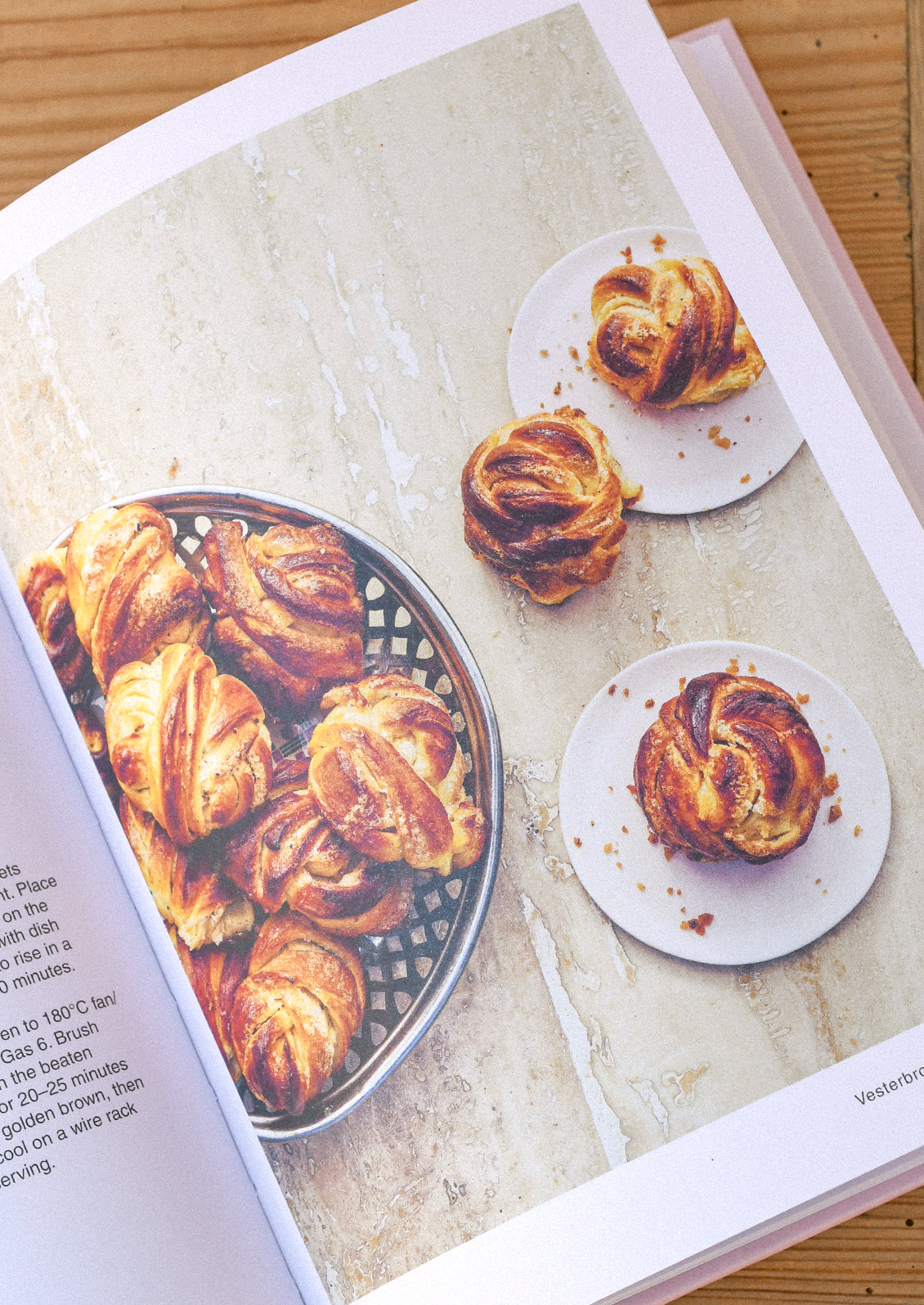 A cookbook open on a table with an image of cardamom buns.