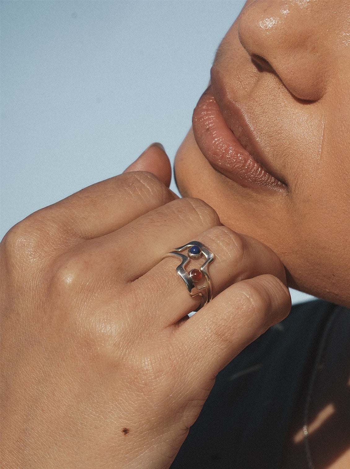 A silver geometric ring with blue and red glass cabochons at open middle.