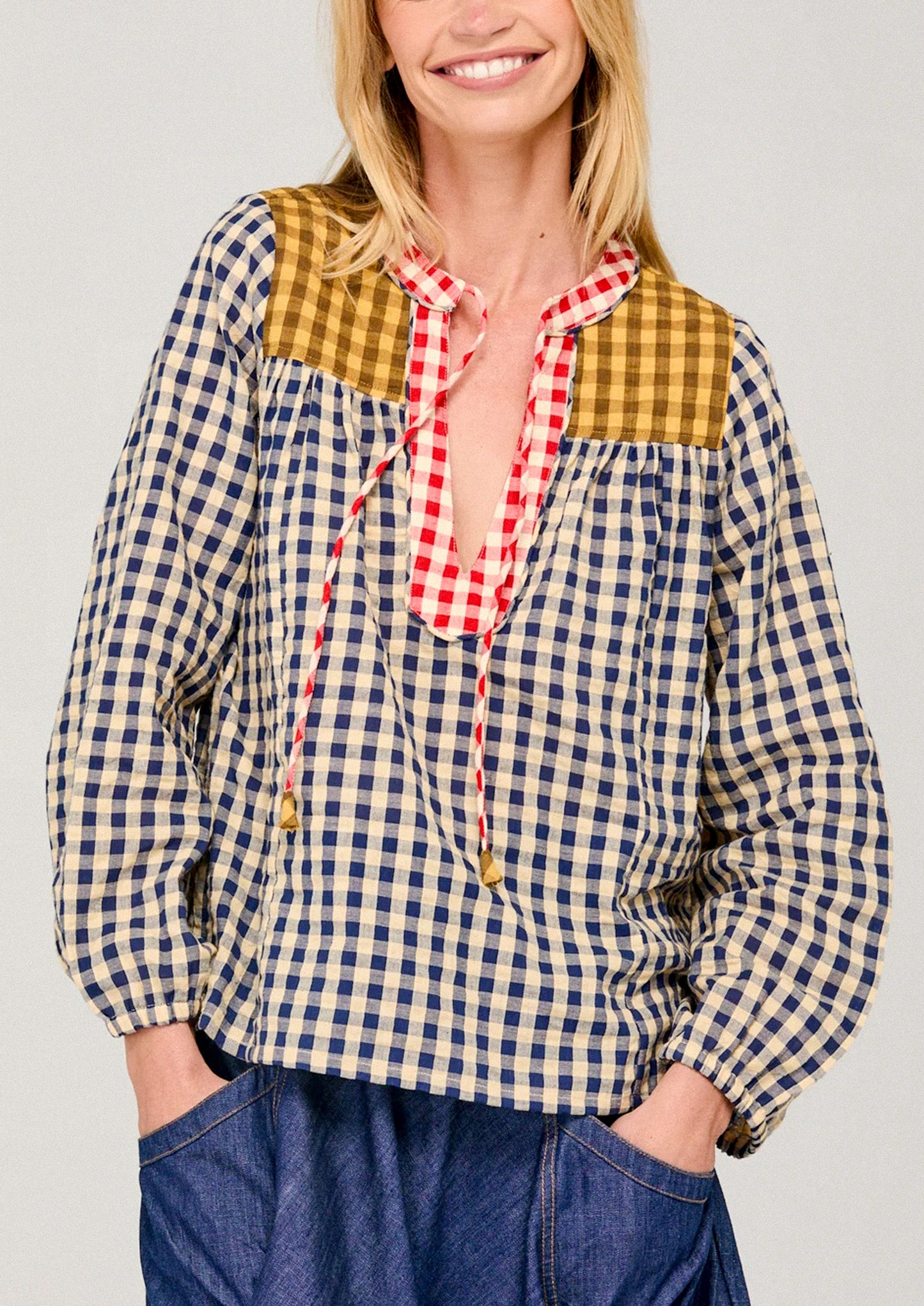 Woman wearing a checkered shirt with a red plaid collar against a plain background