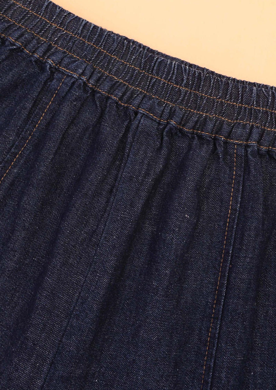 Close-up of dark blue denim fabric with a beige background