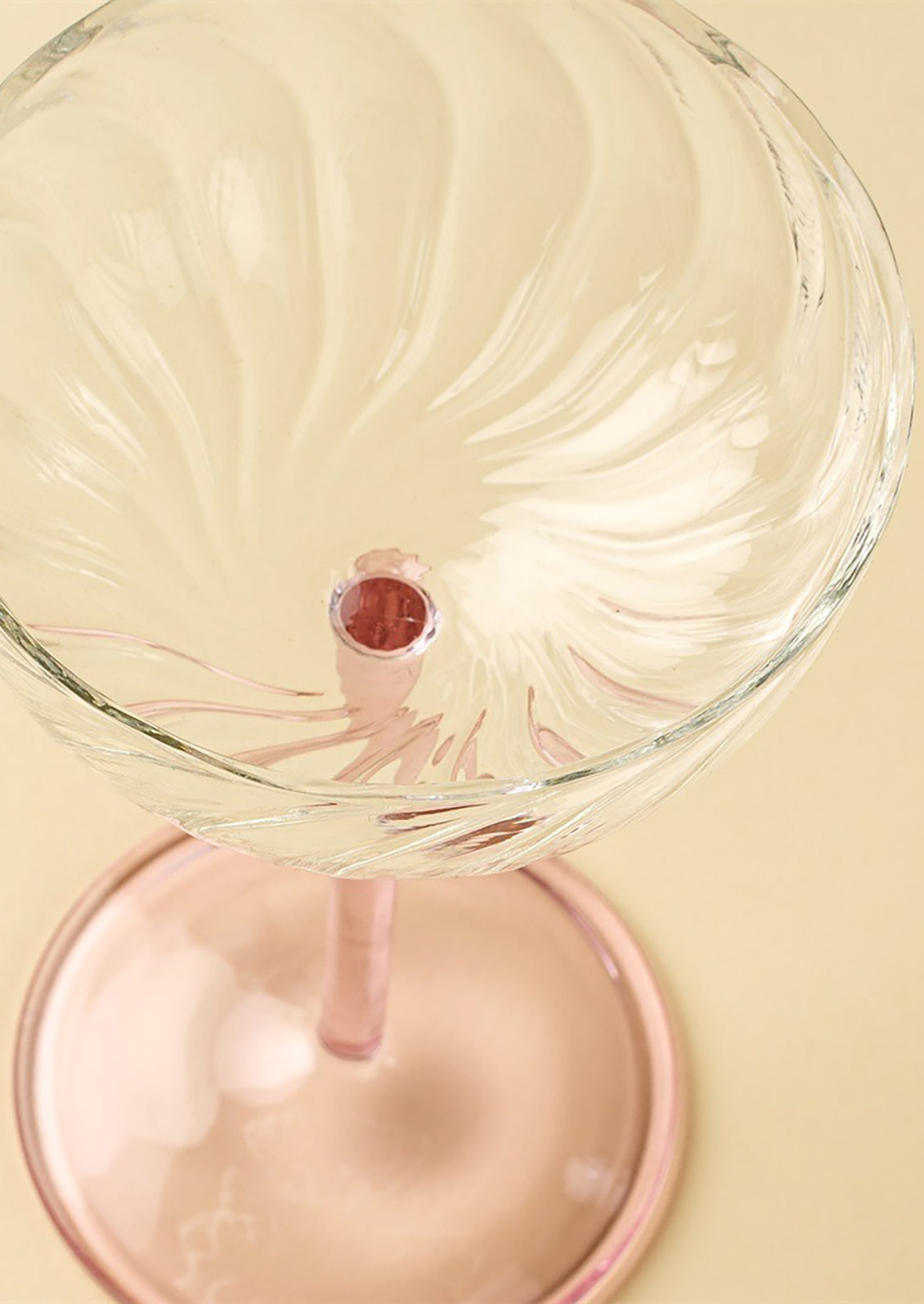 Clear glass with pink base on a beige background