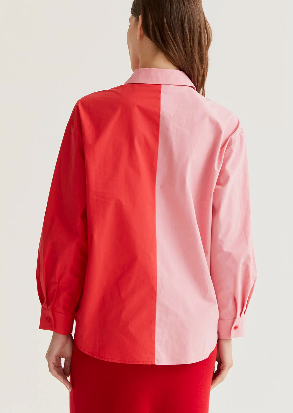 Red and pink color-blocked shirt worn by a person on a white background