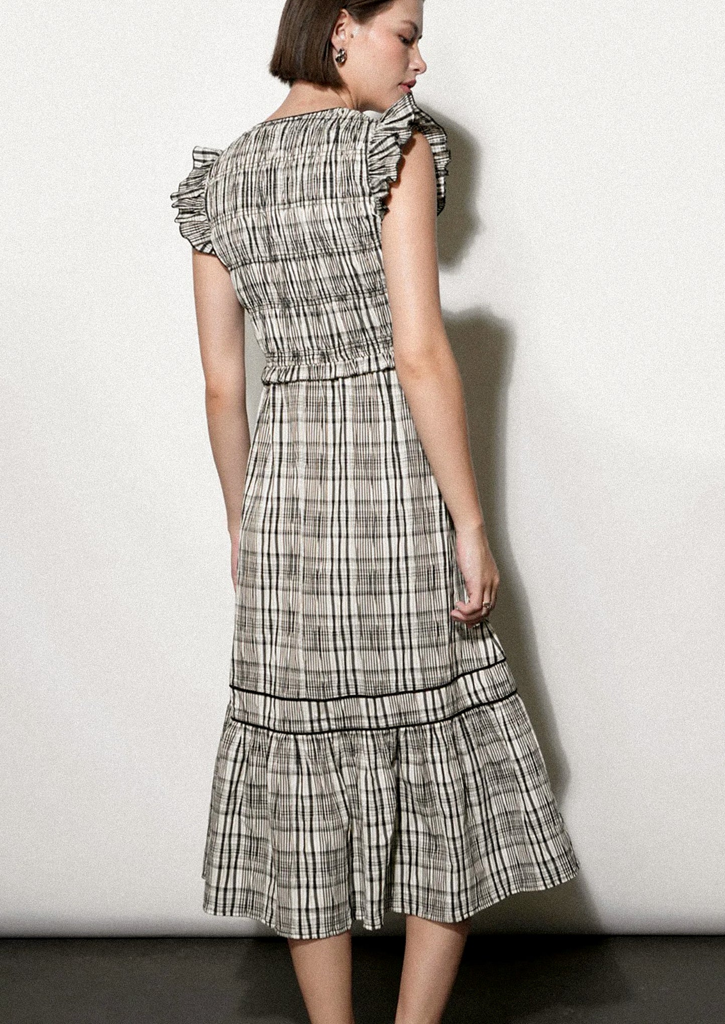 Woman wearing a black and white plaid dress against a white background.