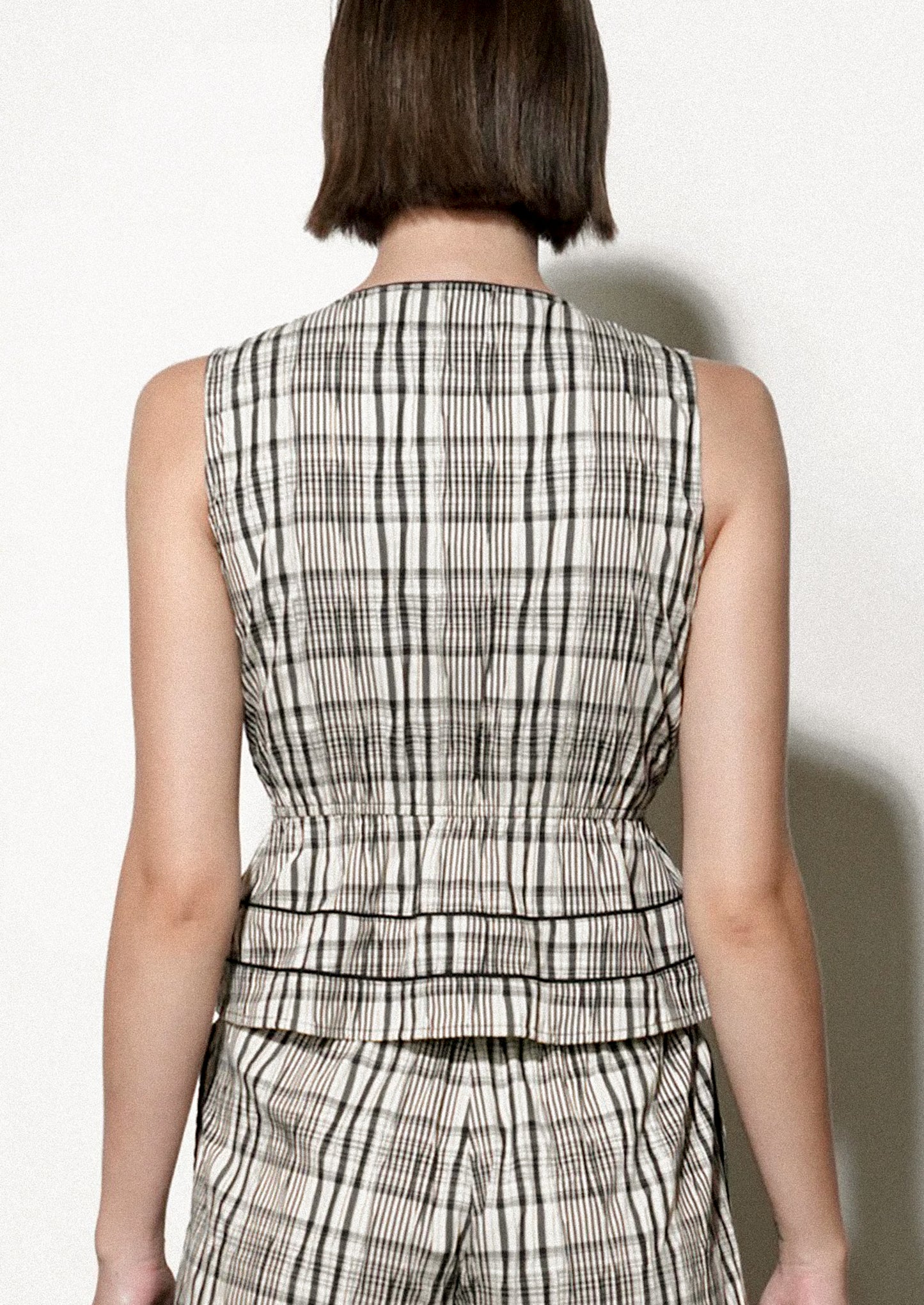 Woman wearing a black and white checkered top against a plain background