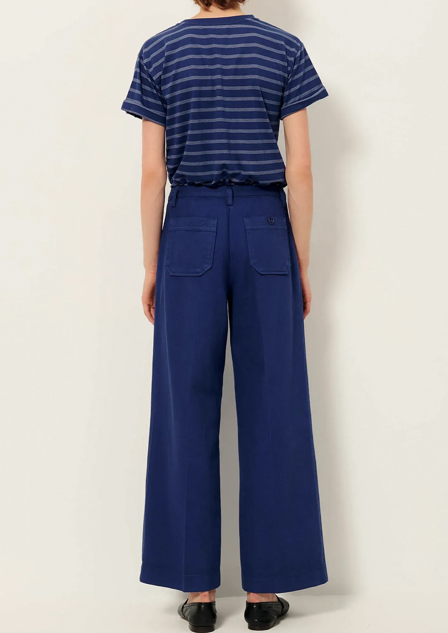 A person wearing a pair of blue wide leg pants with front patch pockets.