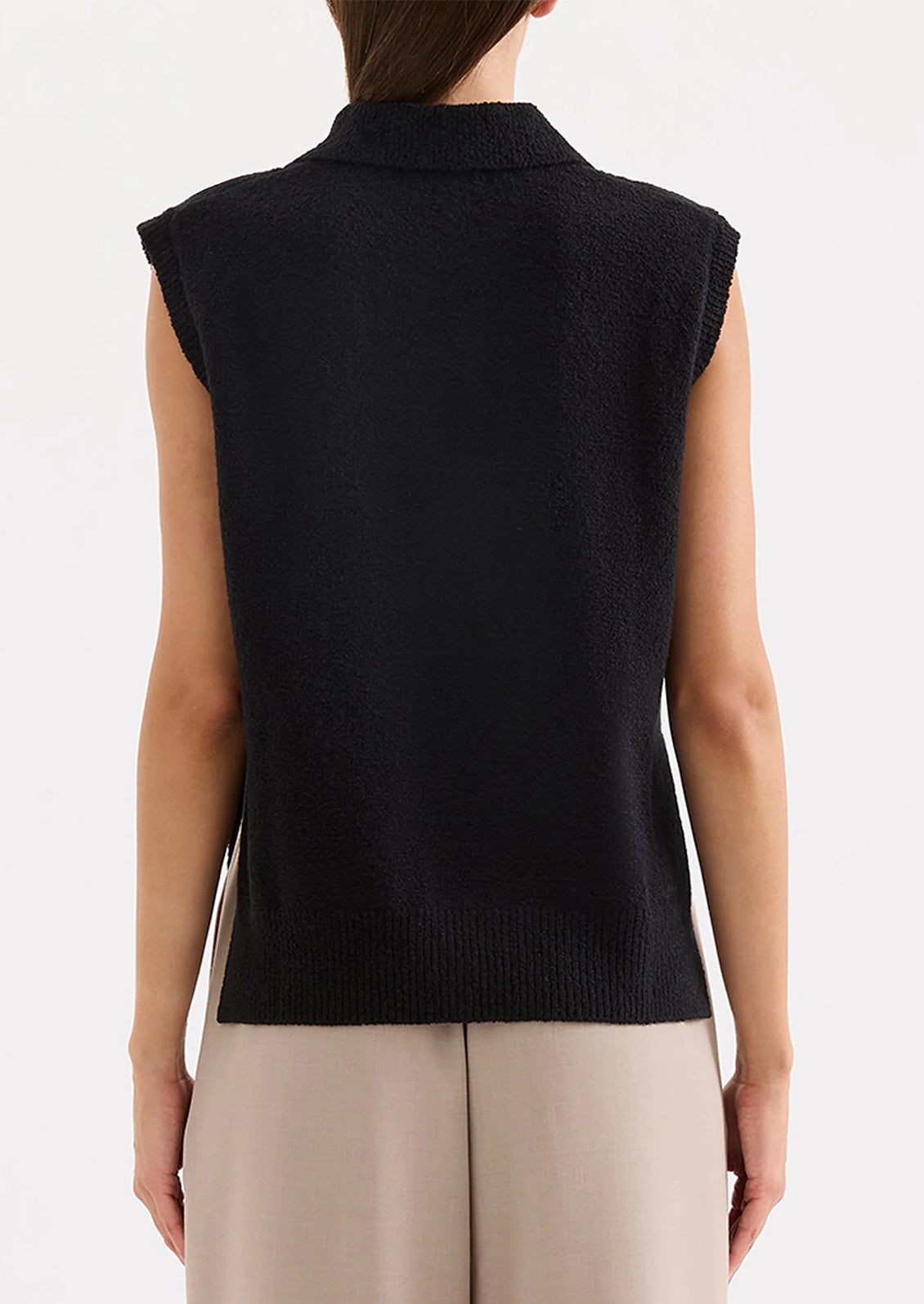 Person wearing a black sleeveless sweater vest on a white background