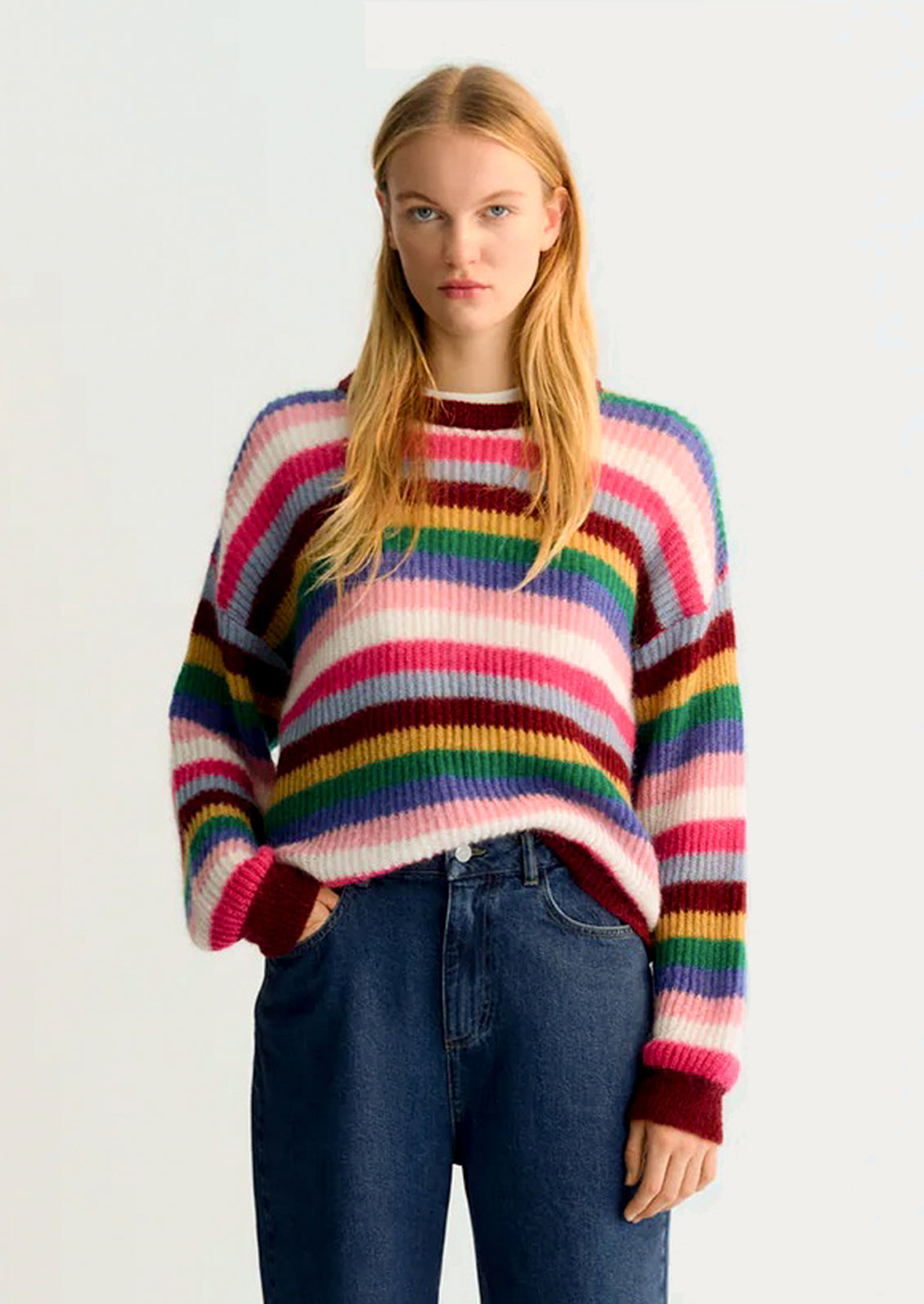 Person wearing a colorful striped sweater on a white background