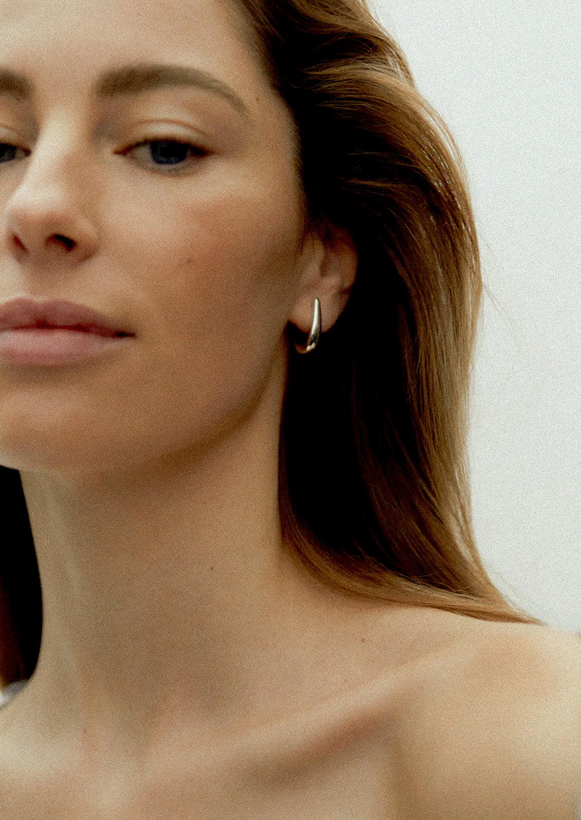 Close-up of a woman wearing a hoop earring with a neutral background