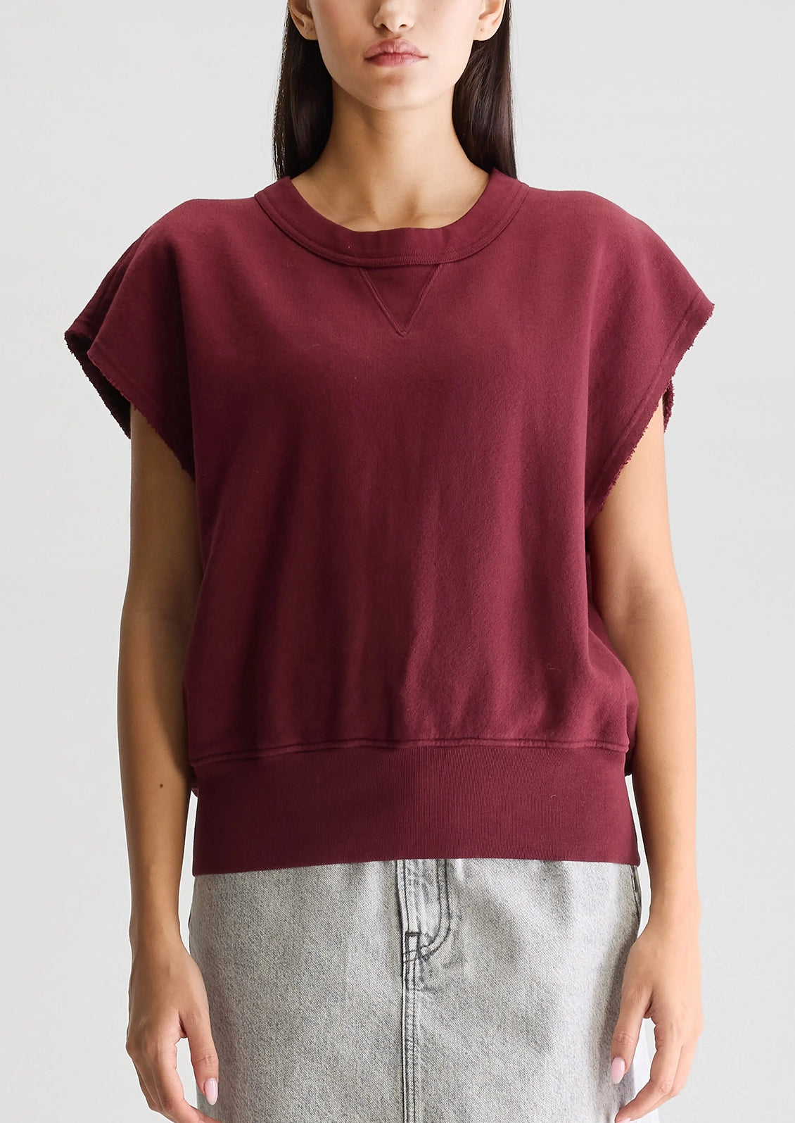 A woman wearing a burgundy cut-off sweatshirt.