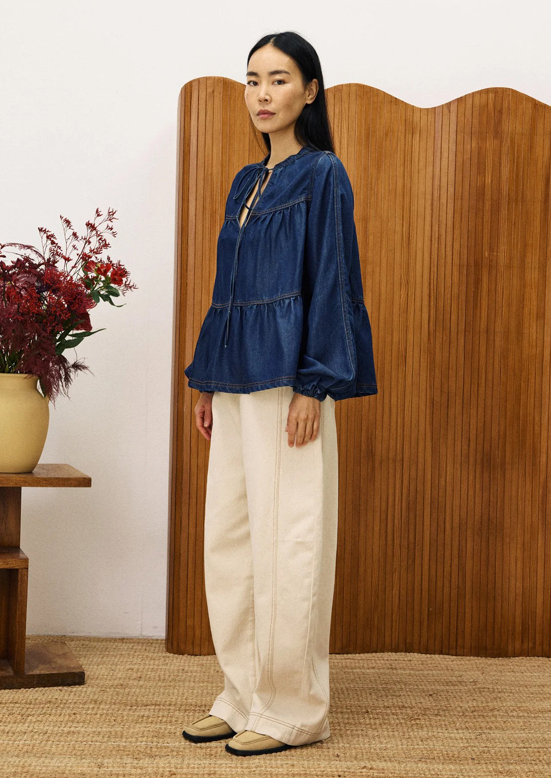 A woman wearing a denim top with shirred ruching.