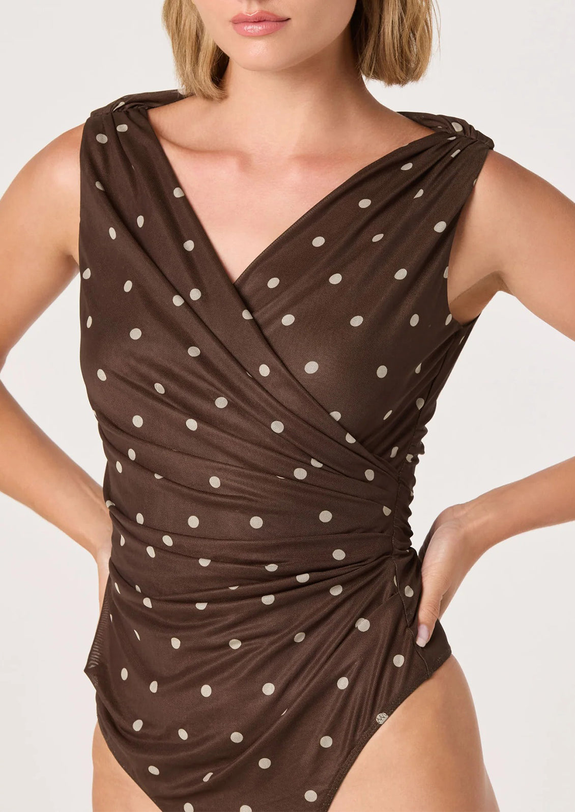 A person wearing a bodysuit in brown with cream polka dots.