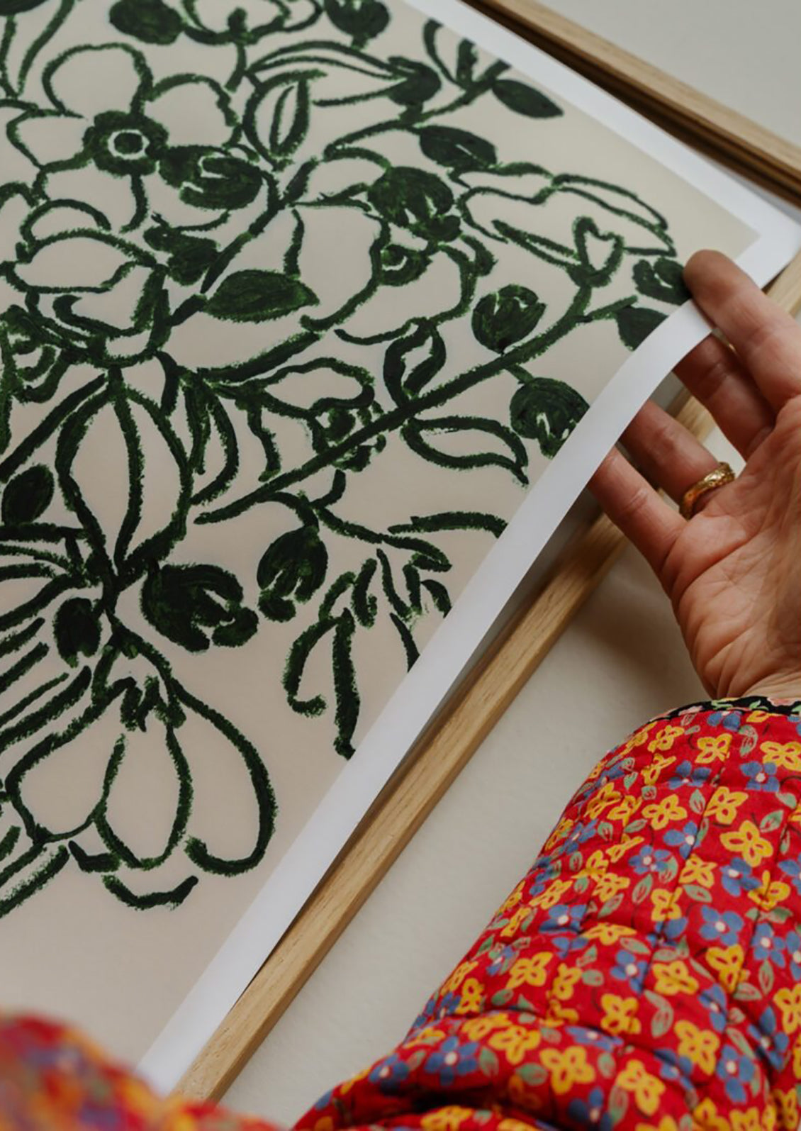 Person holding a floral patterned fabric with green design on a white background