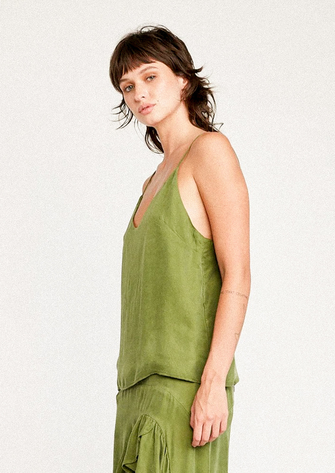A person wearing a cupro camisole in kelp green.