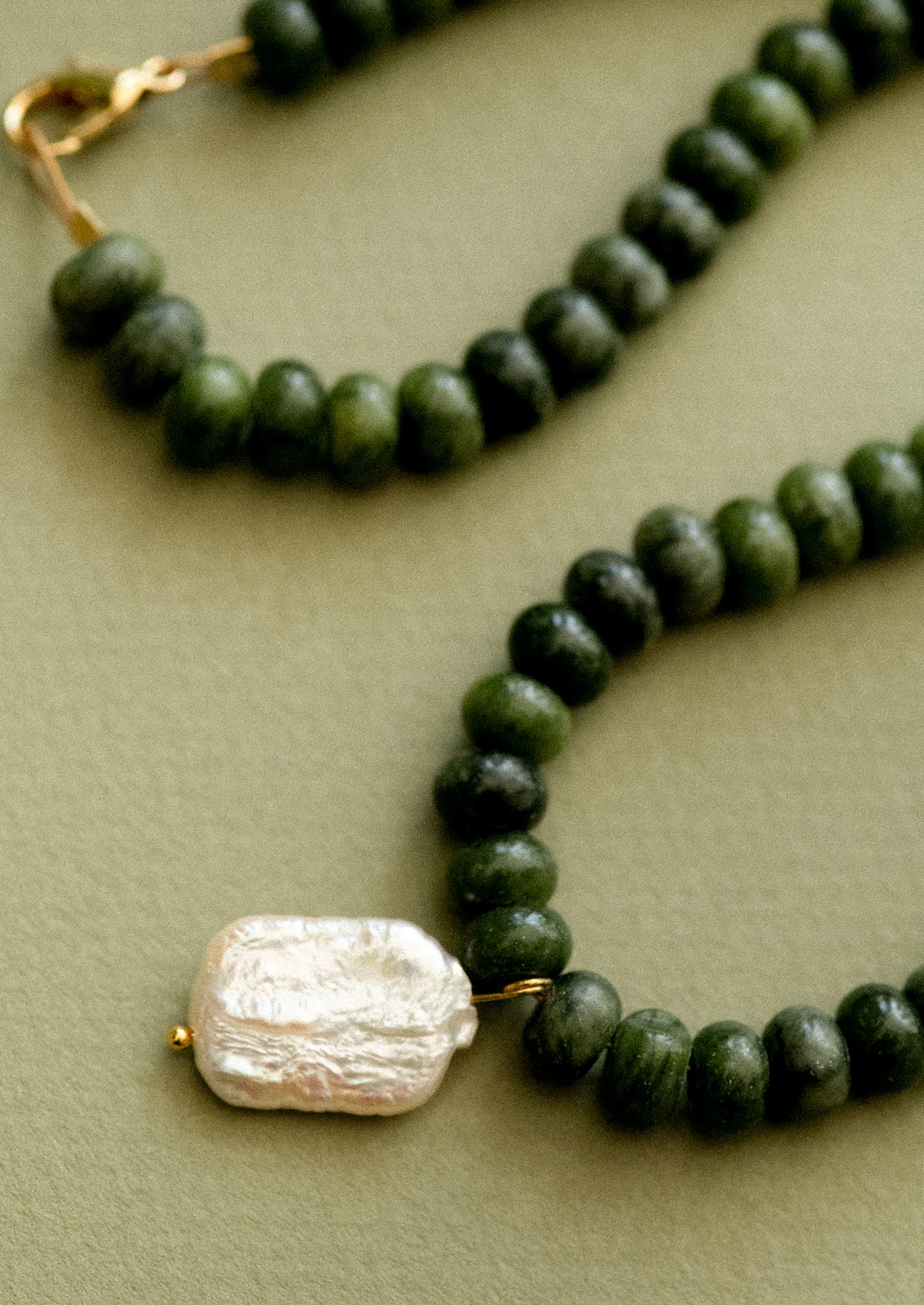 A necklace with jade beads and pearl pendant.