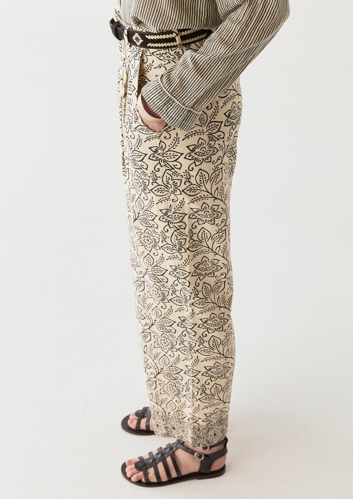 A woman wearing a pair of cream pants with black floral print.