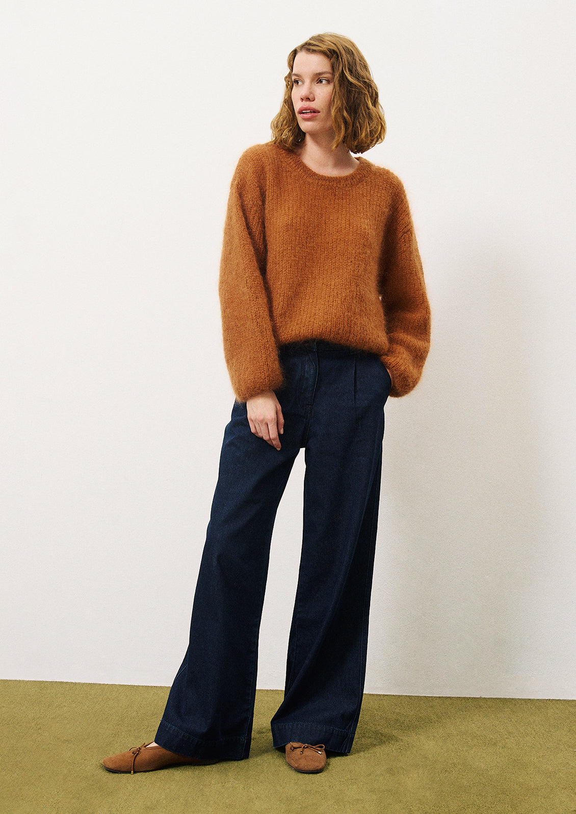 A woman wearing a pair of wide leg trouser style jeans in dark inky denim.