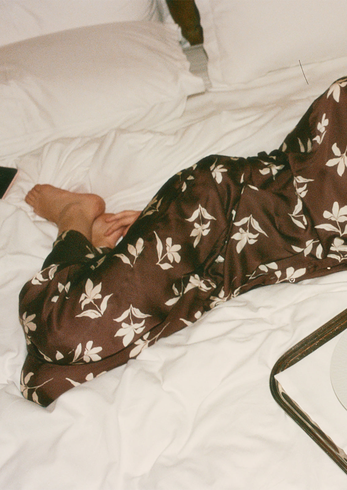 A person wearing a matching set of brown and white floral pajama style clothes.