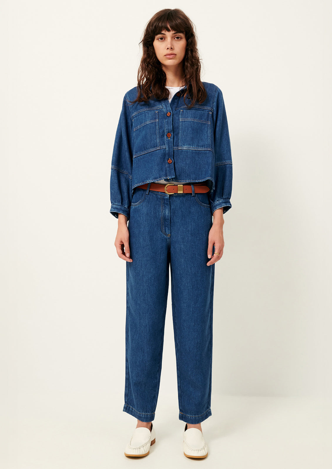 A woman wearing a denim jacket and pants in rich blue denim.