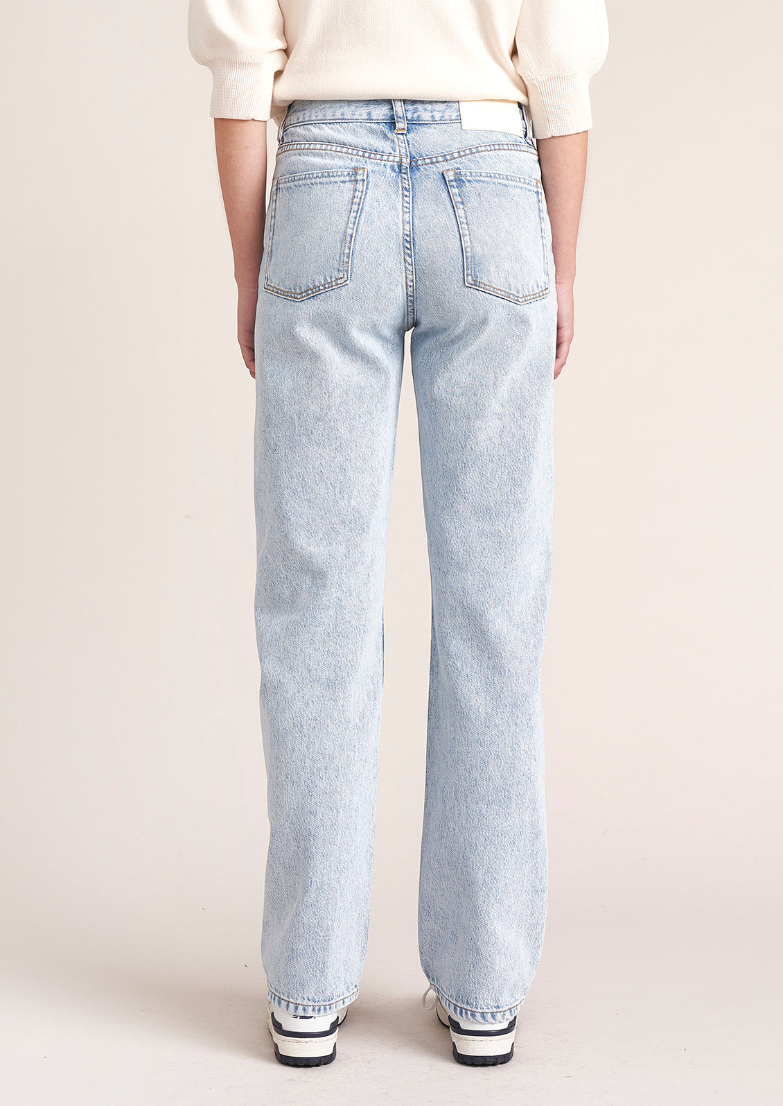 A person wearing a pair of light wash straight leg jeans.