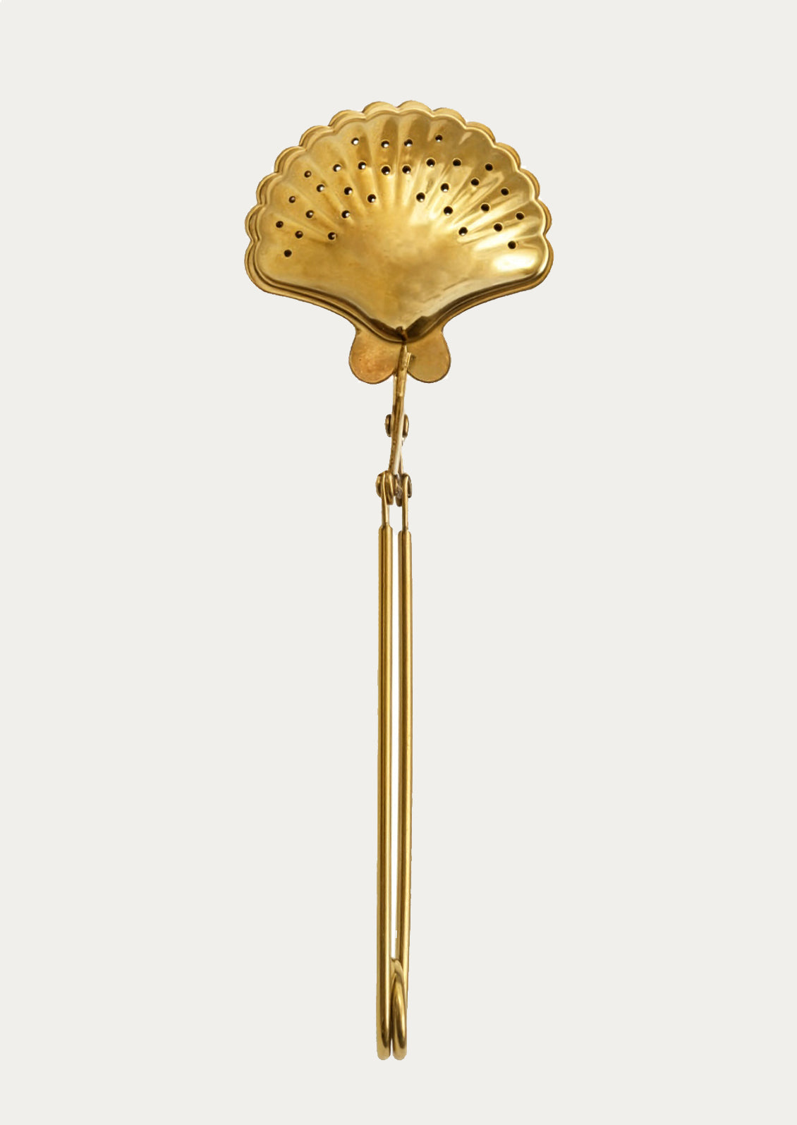 Gold shell-shaped tea infuser on a white background