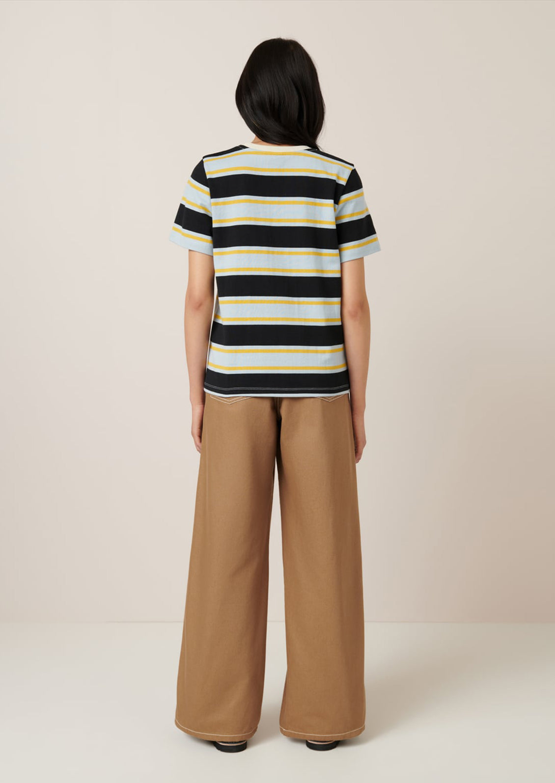 A person wearing a t-shirt with light blue, black and yellow rugby stripe pattern.