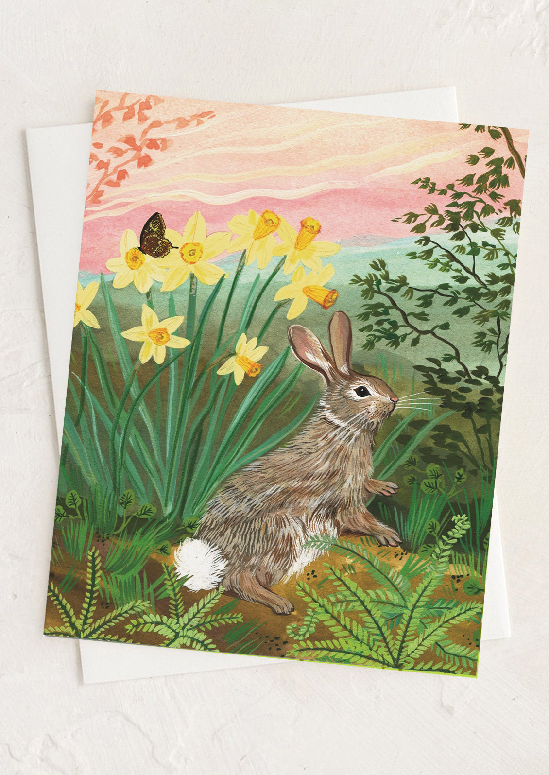 Greeting card with a rabbit and daffodils in a garden setting