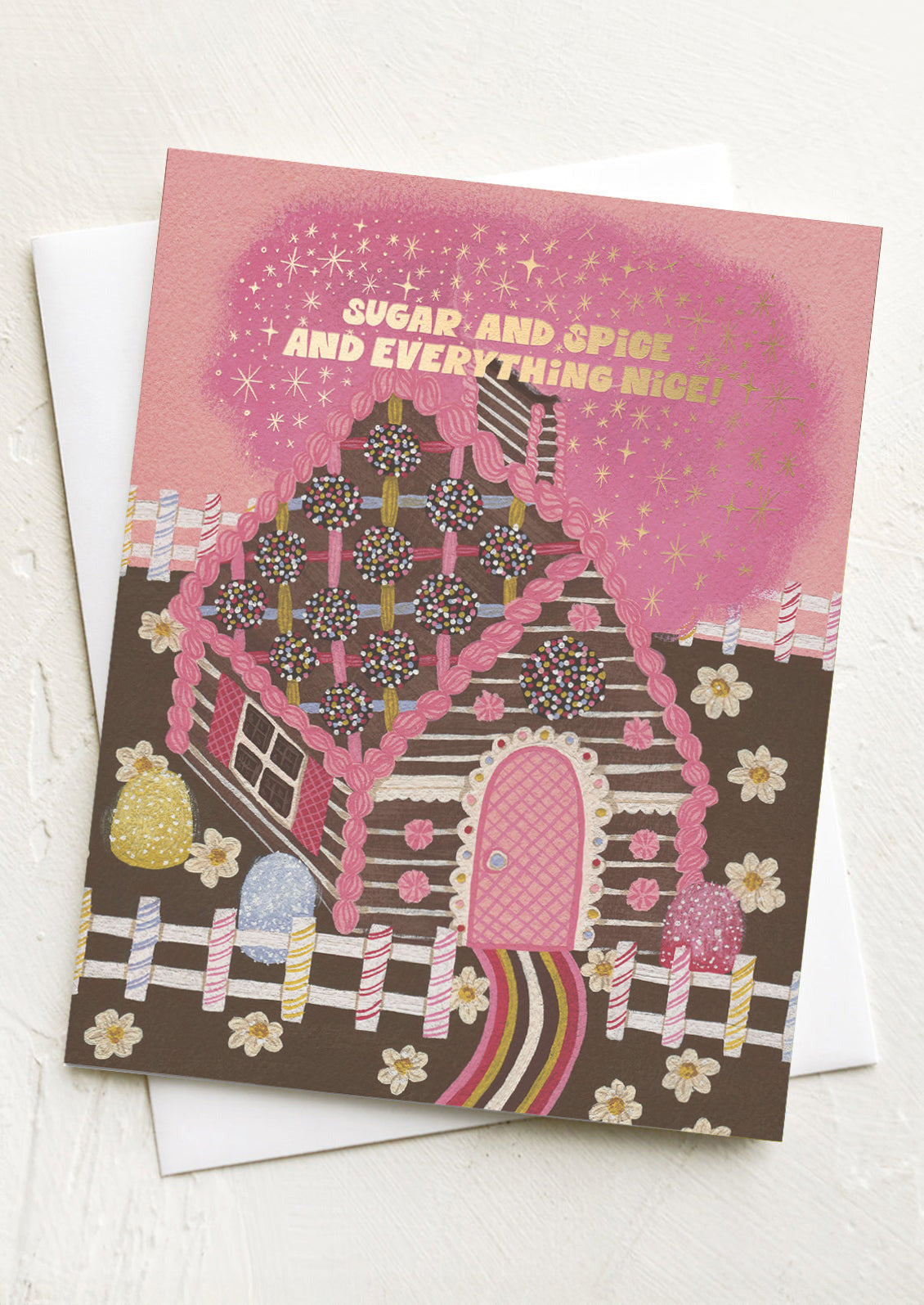 Greeting card with a gingerbread house design and text 'Sugar and Spice and Everything Nice' on a pink background.