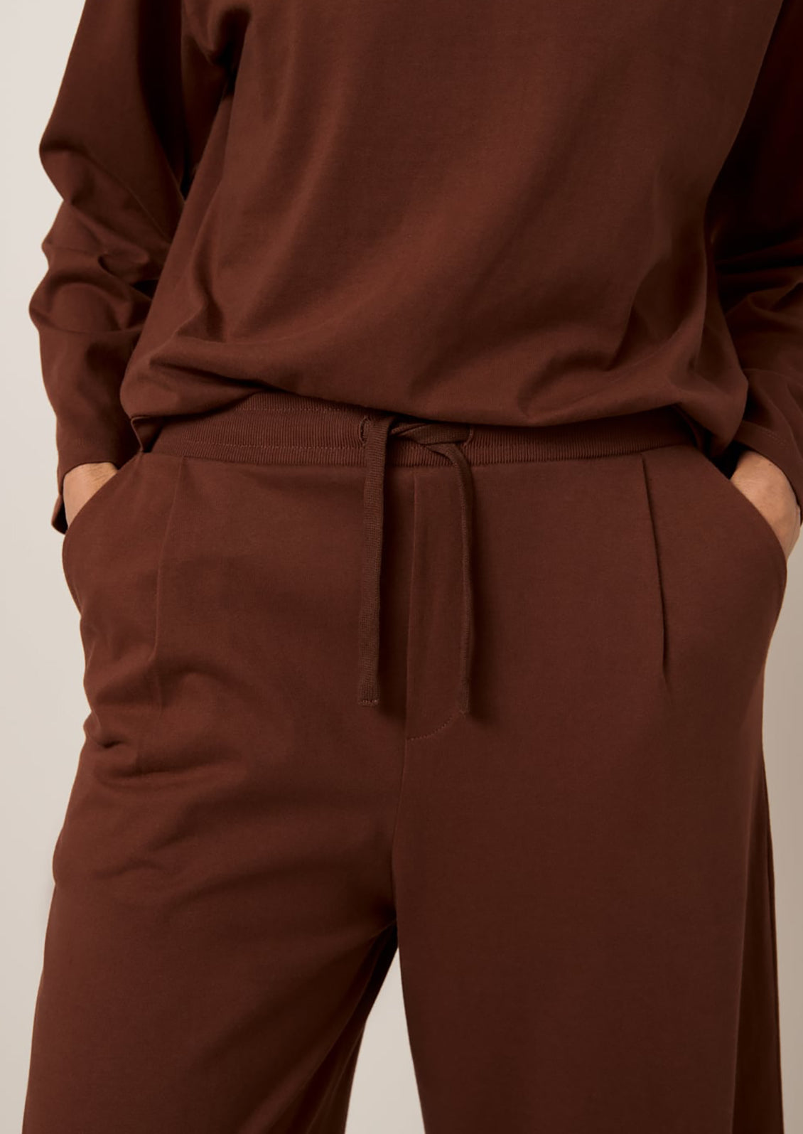 A person wearing a pair of wide leg pants in sequoia brown color.