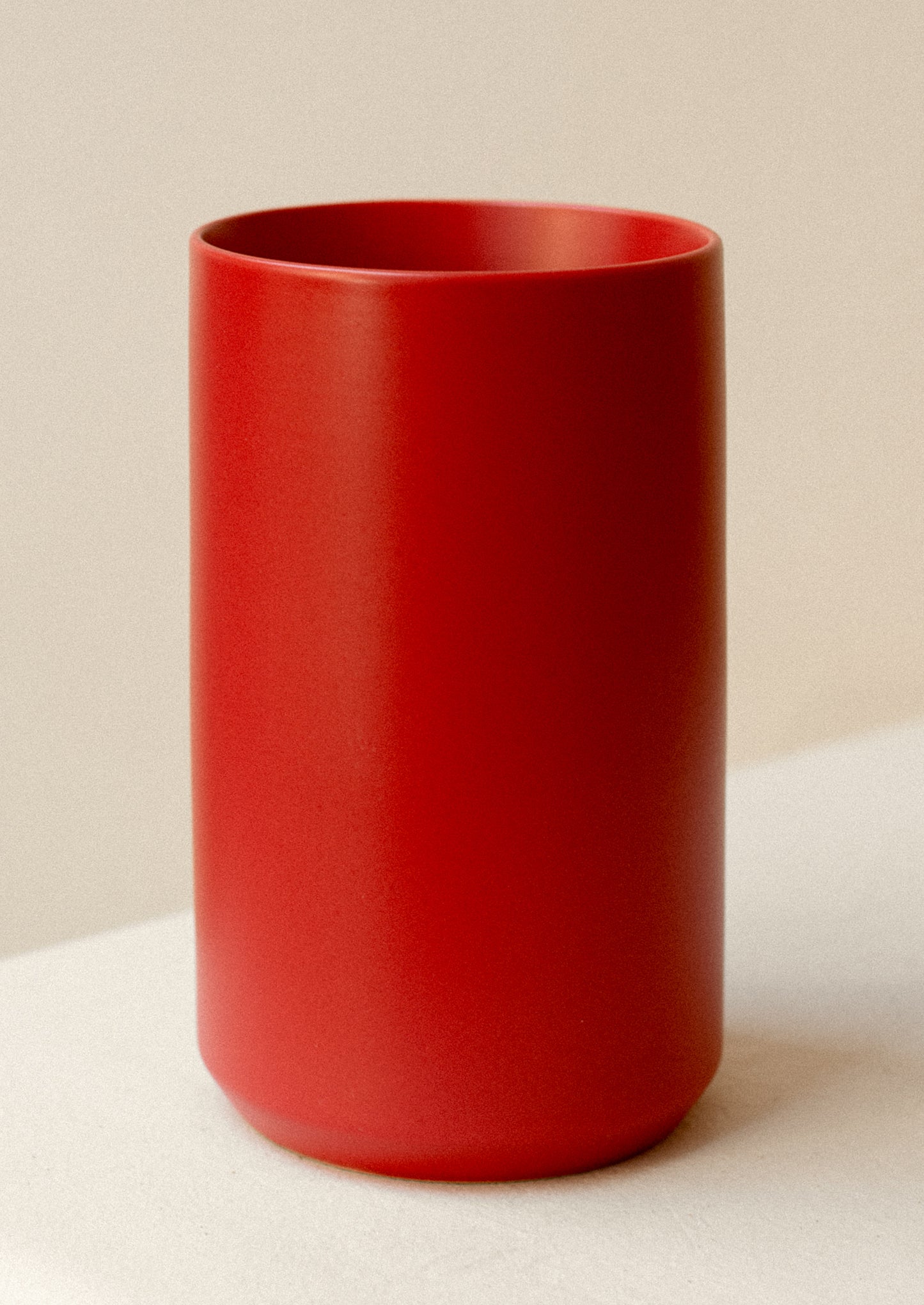 A cylinder shape vase in matte red ceramic.