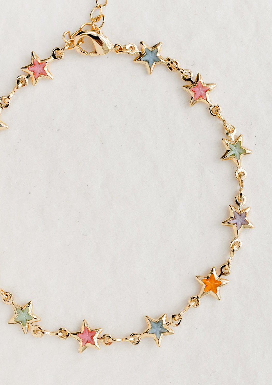 A gold bracelet with pastel colored glass star stations throughout.