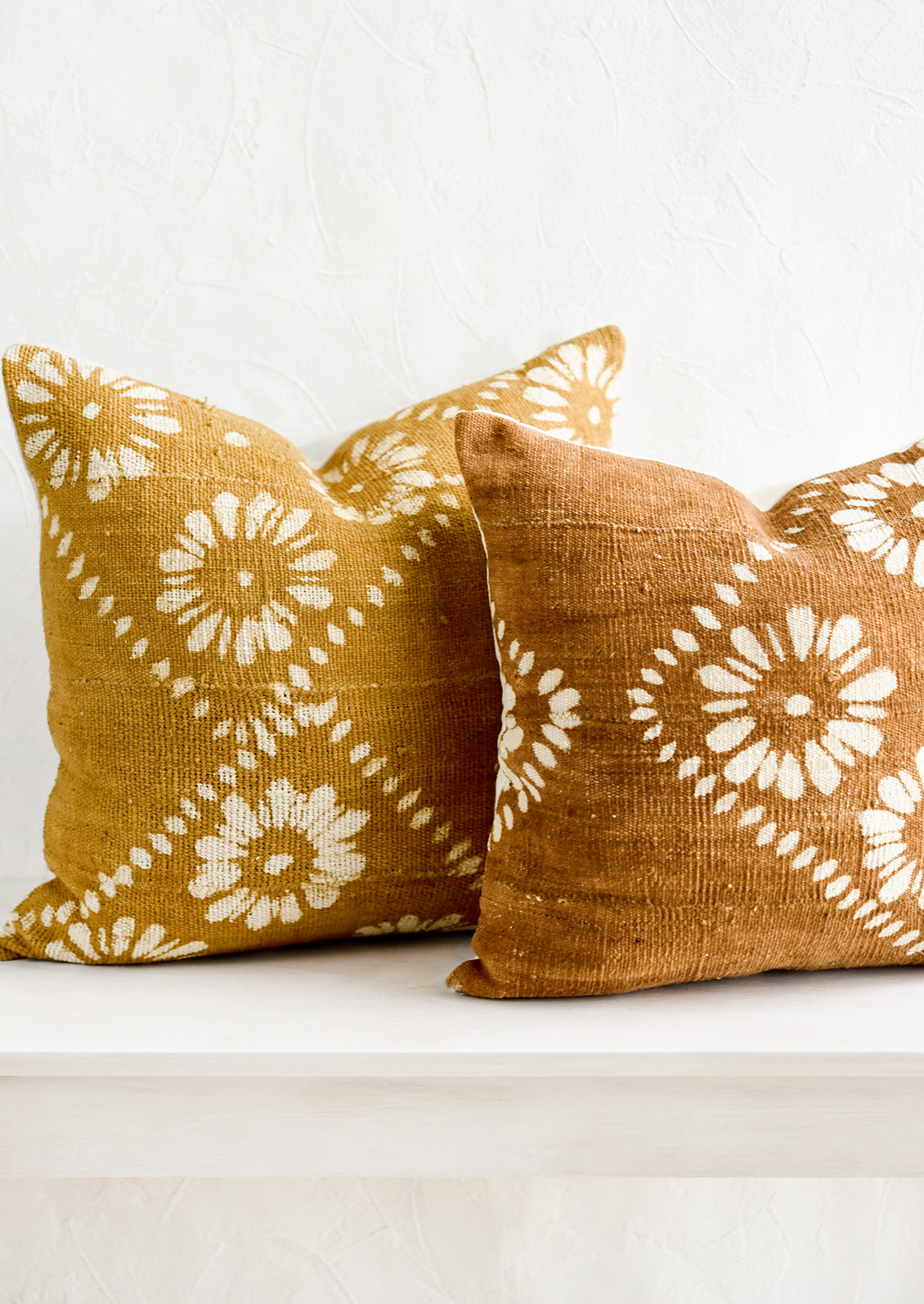 Mustard and brown mudcloth pillows with white floral motif.