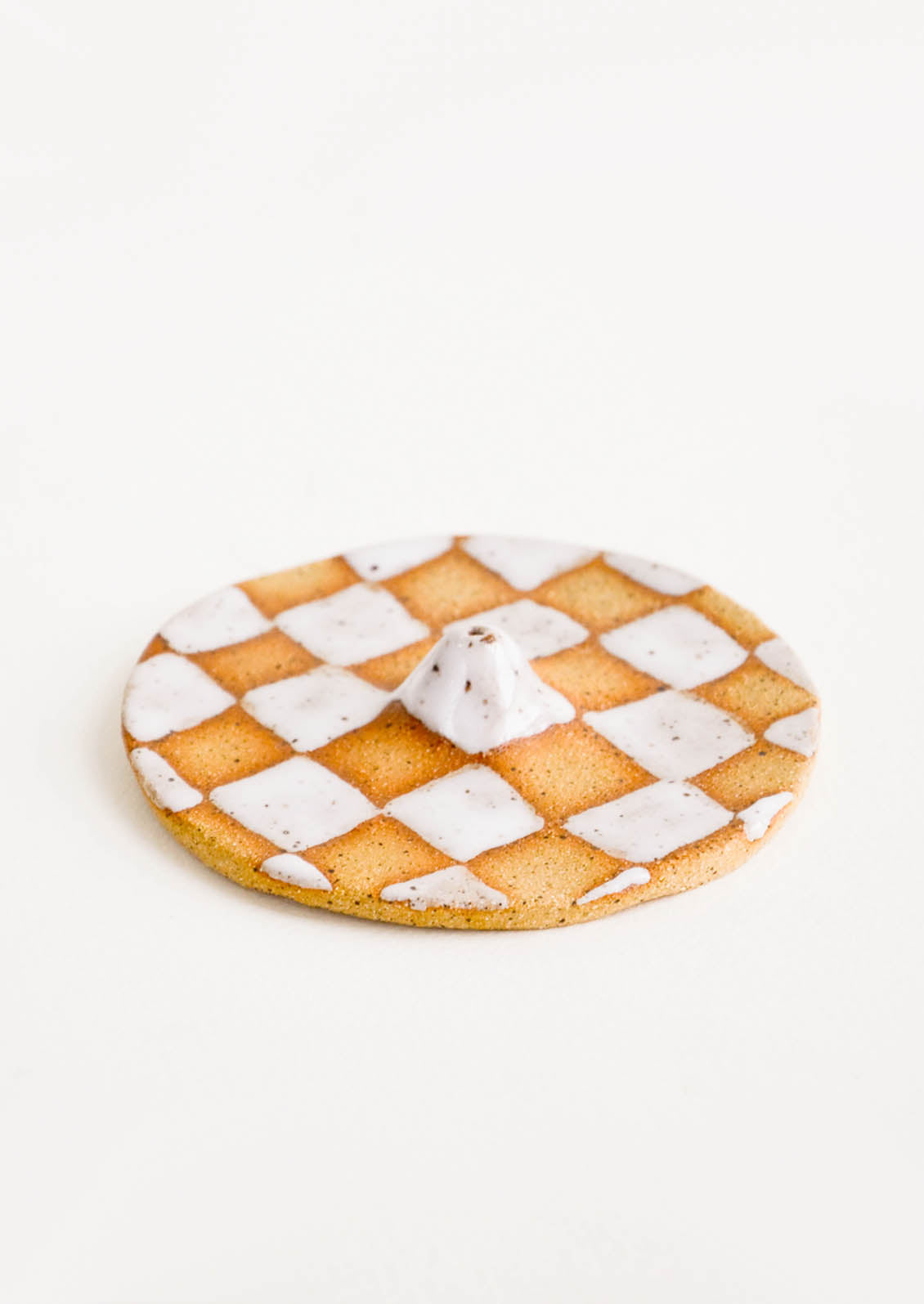 A handmade ceramic incense holder in white checkered pattern.