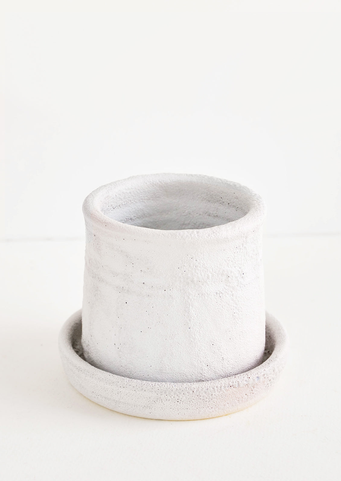 Round planter with saucer, allover heavy and crater-like texture in cool white matte glaze