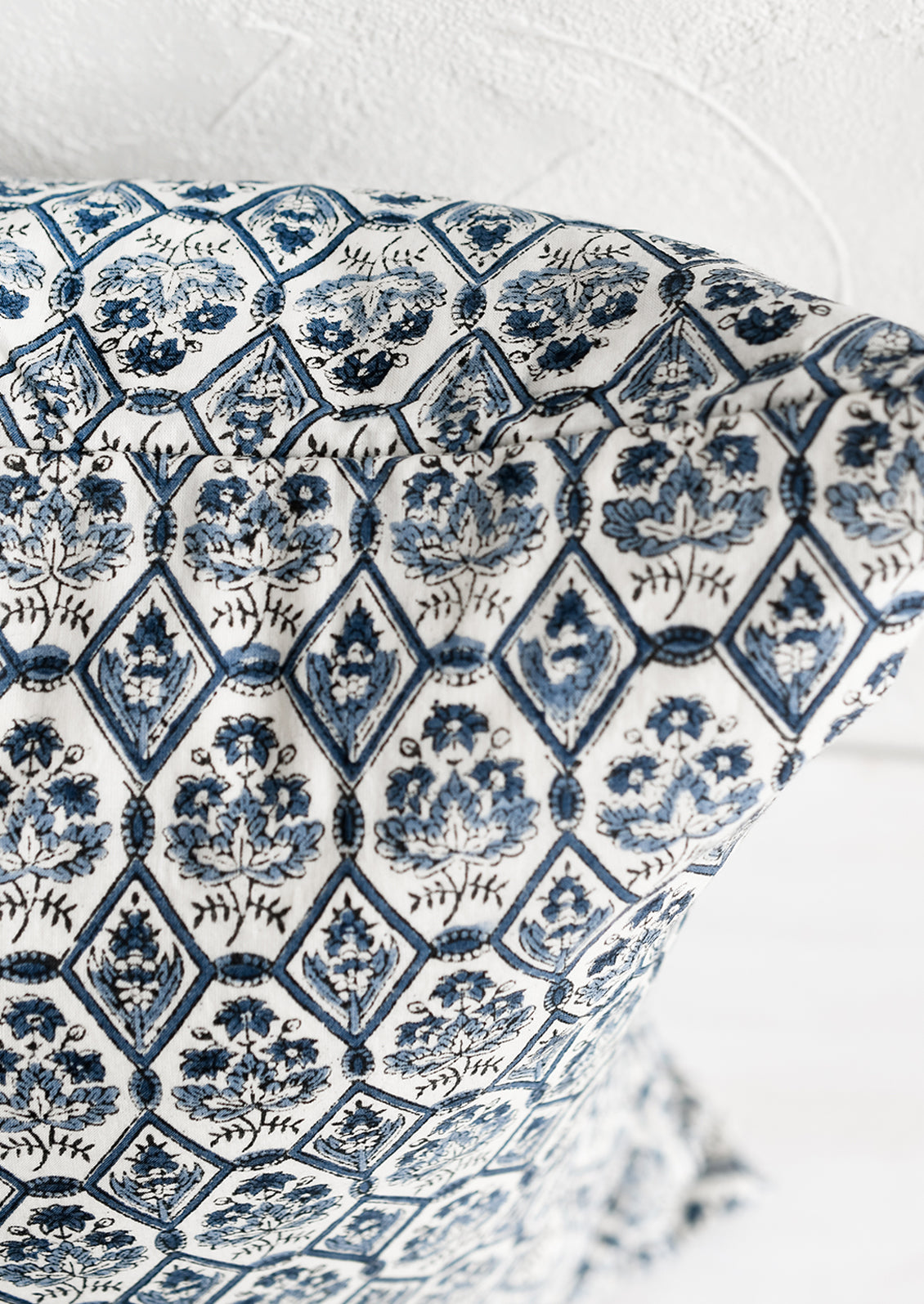 A block printed pillow in blue and white tile print.