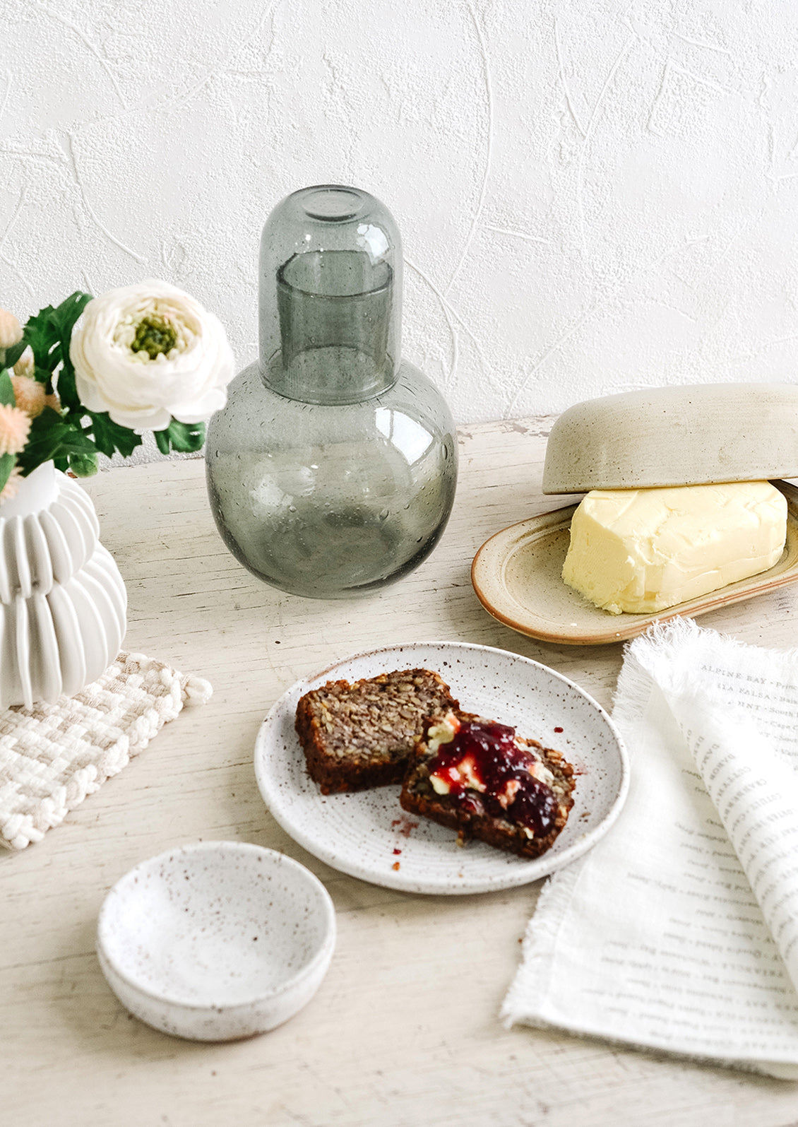 An arrangement of tableware artfully arranged atop a rustic white table.