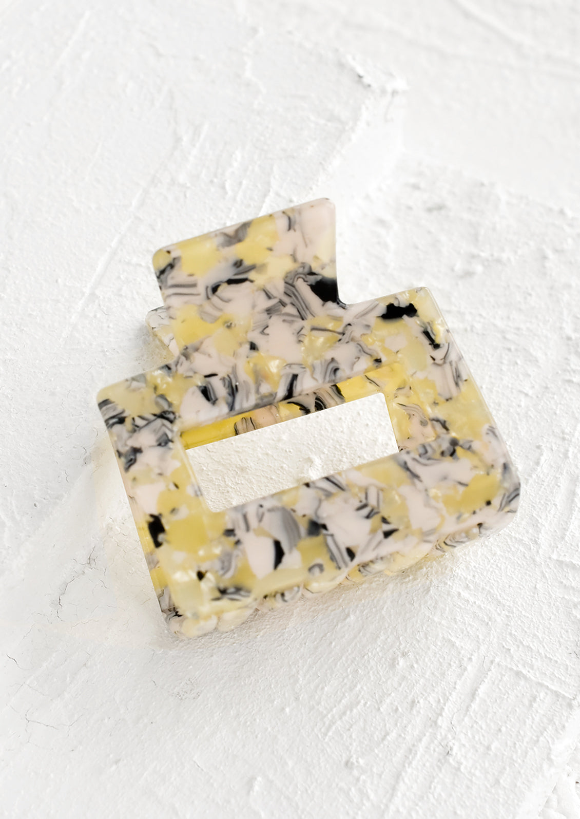 A marbled hair clip in yellow and pink marble.
