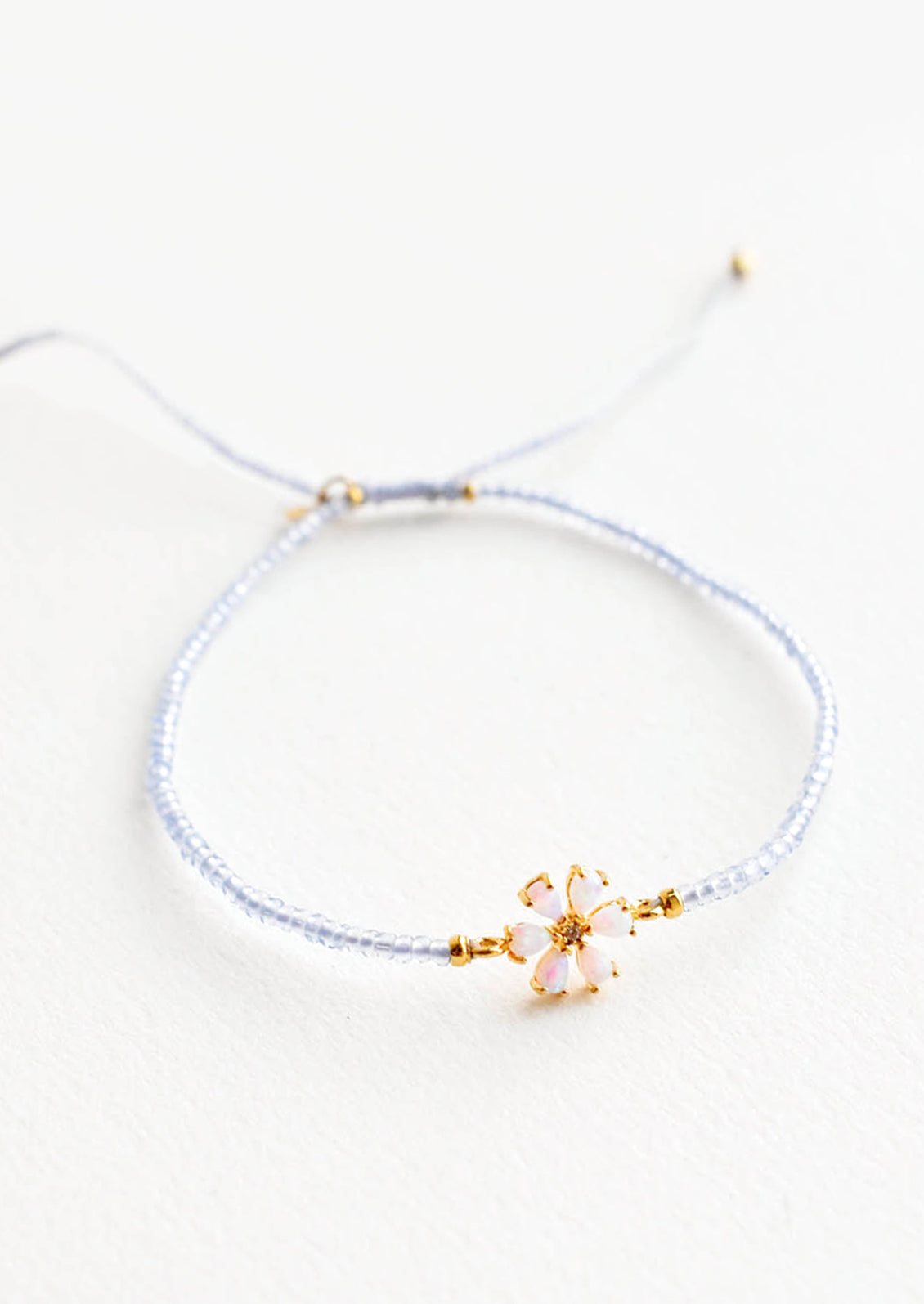 A delicate bracelet of pale blue glass beads and a small iridescent gam flower charm.