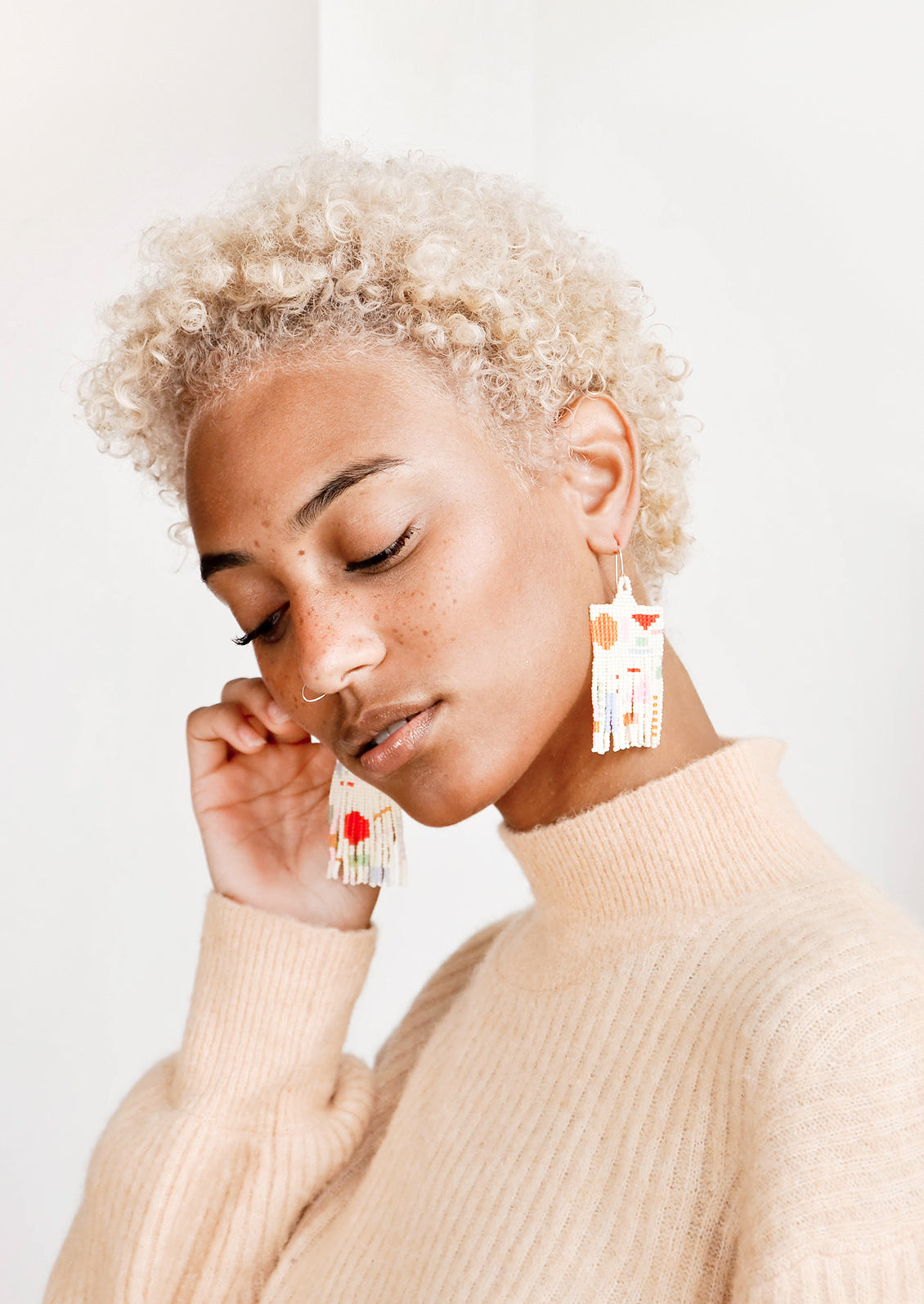 Model wears fringe earrings of cream and multicolored beads.