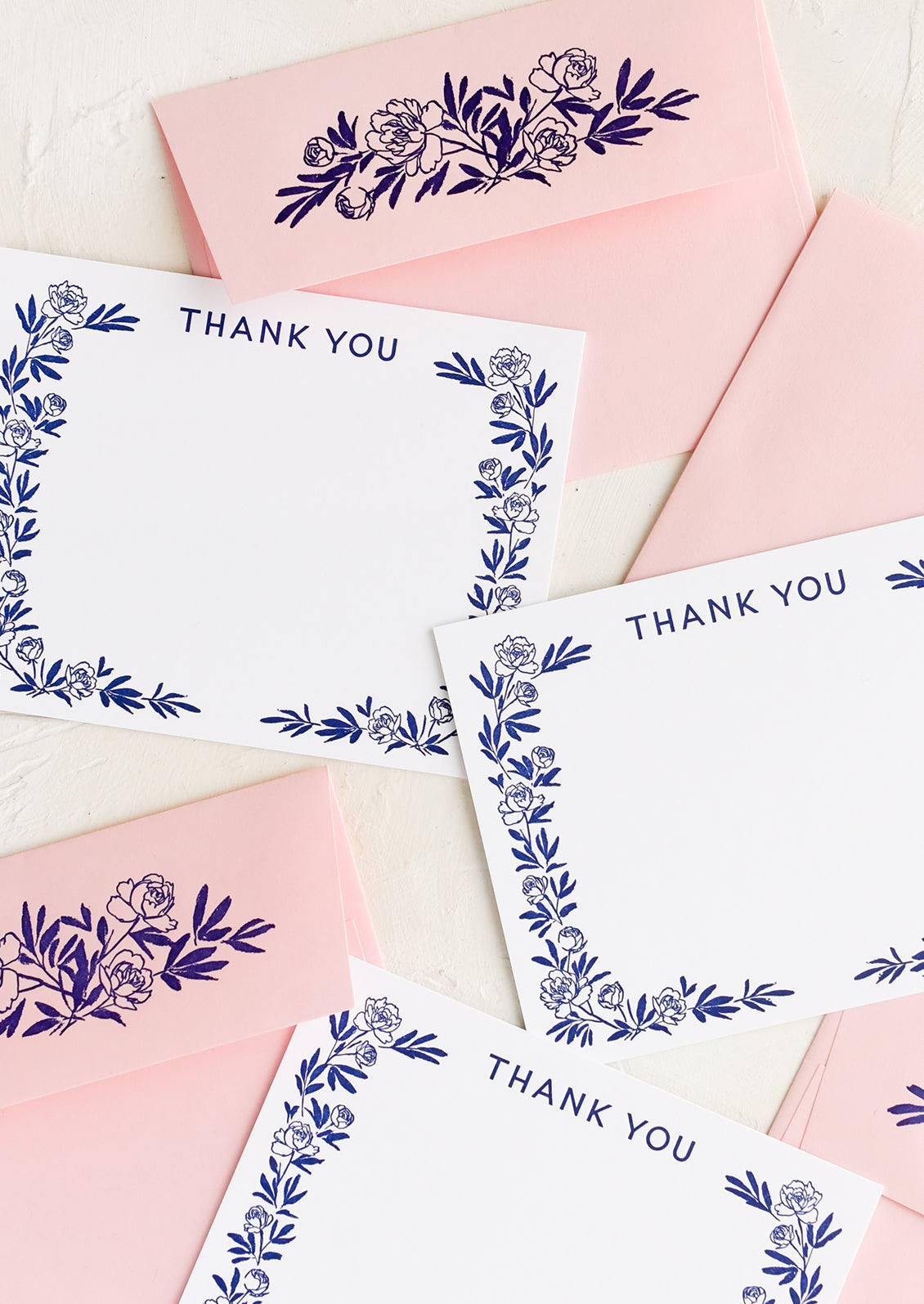 A set of white flat notecards with peony border and "Thank you" written at top.
