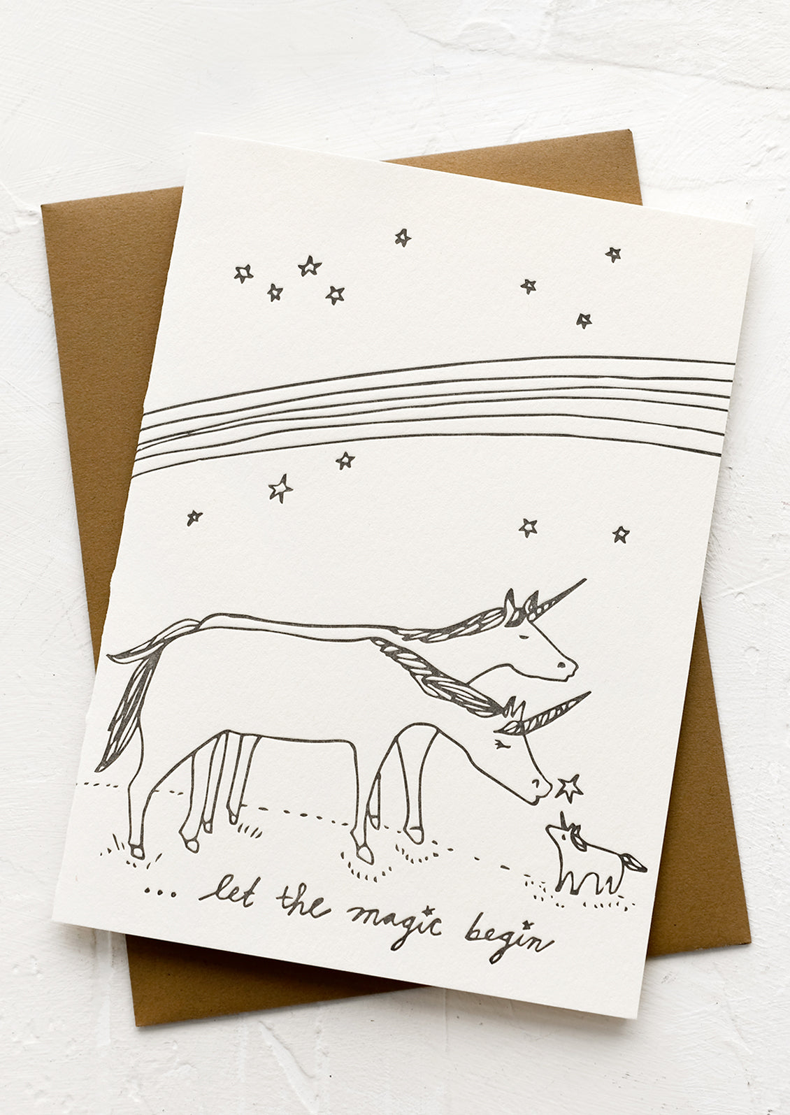 A greeting card with illustration of unicorn family, text reads "Let the magic begin".