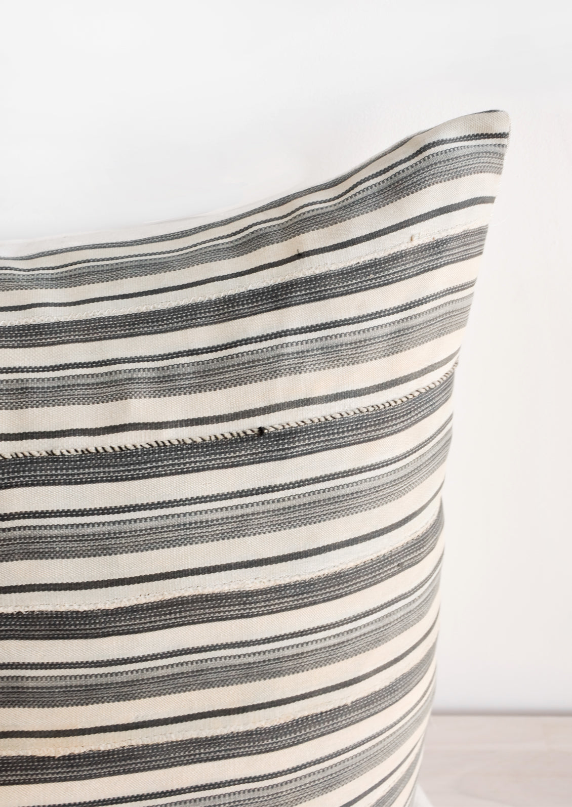 Close up of fabric on throw pillow in faded vintage fabric with allover tan and grey stripes