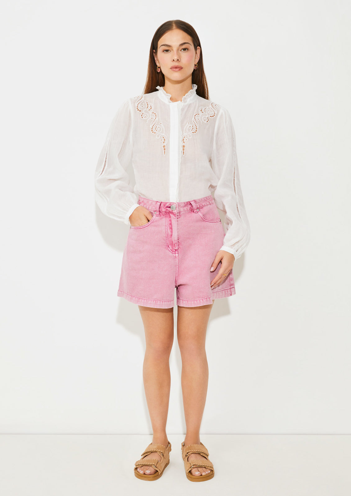 A woman wearing a white linen blouse with ruffled collar and cutwork embroidery detailing.