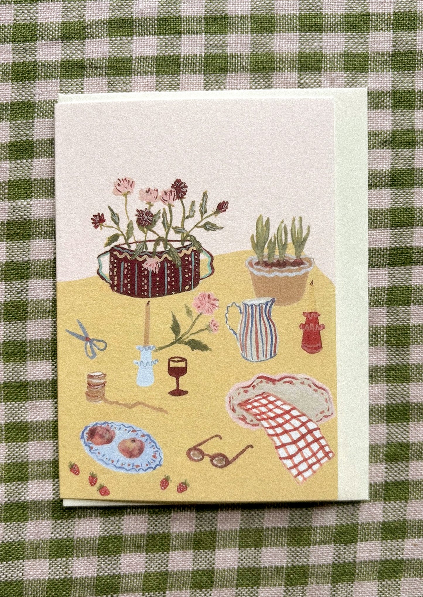 Illustrated card with various objects on a checkered fabric background