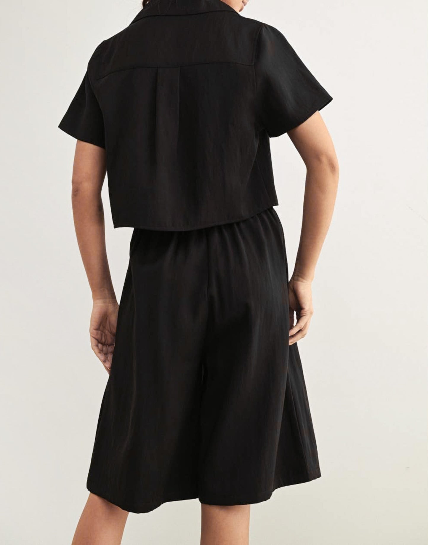 A person wearing a pair of tailored knee-length shorts in black.