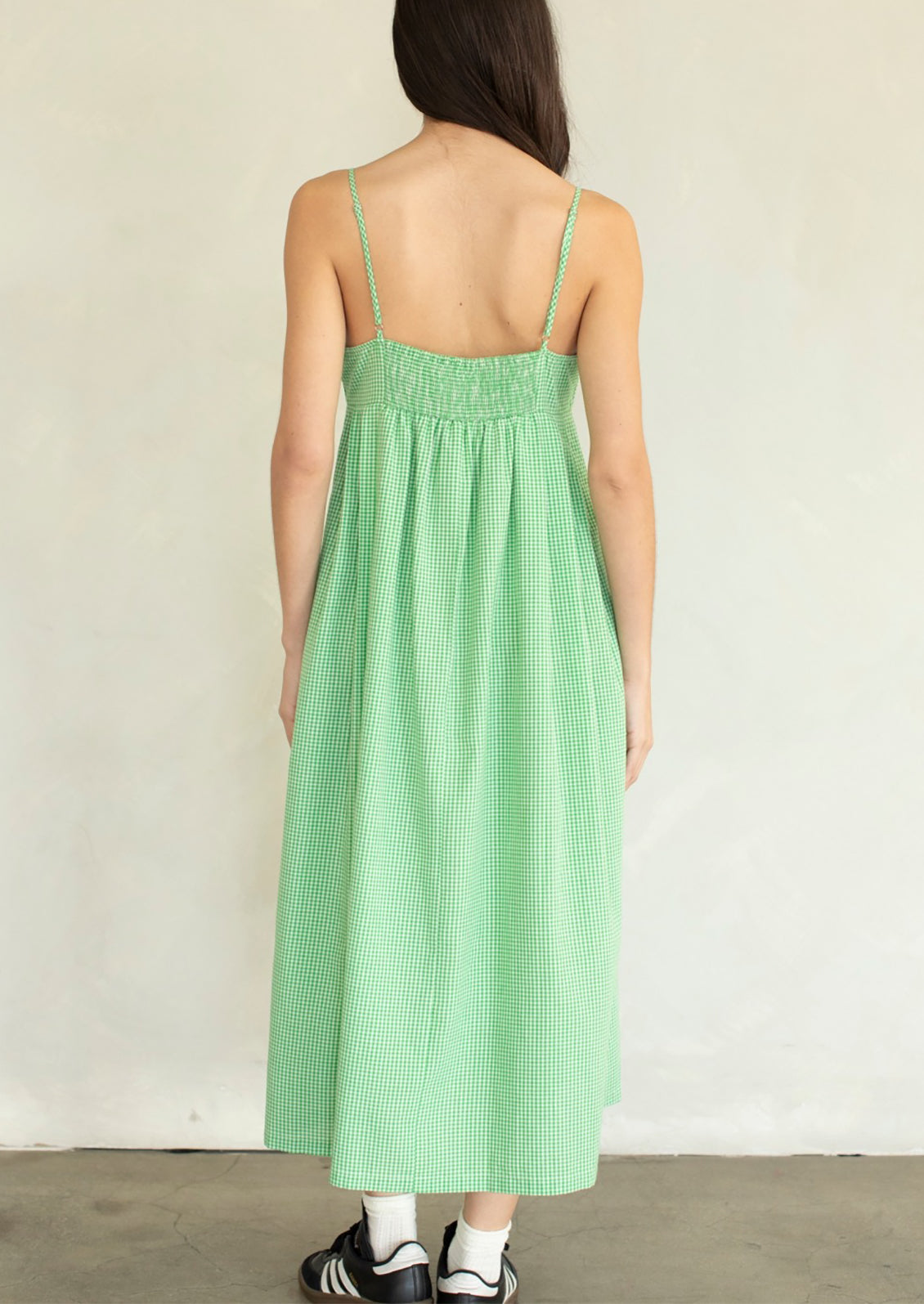 A person wearing a calf-length dress in micro green gingham.