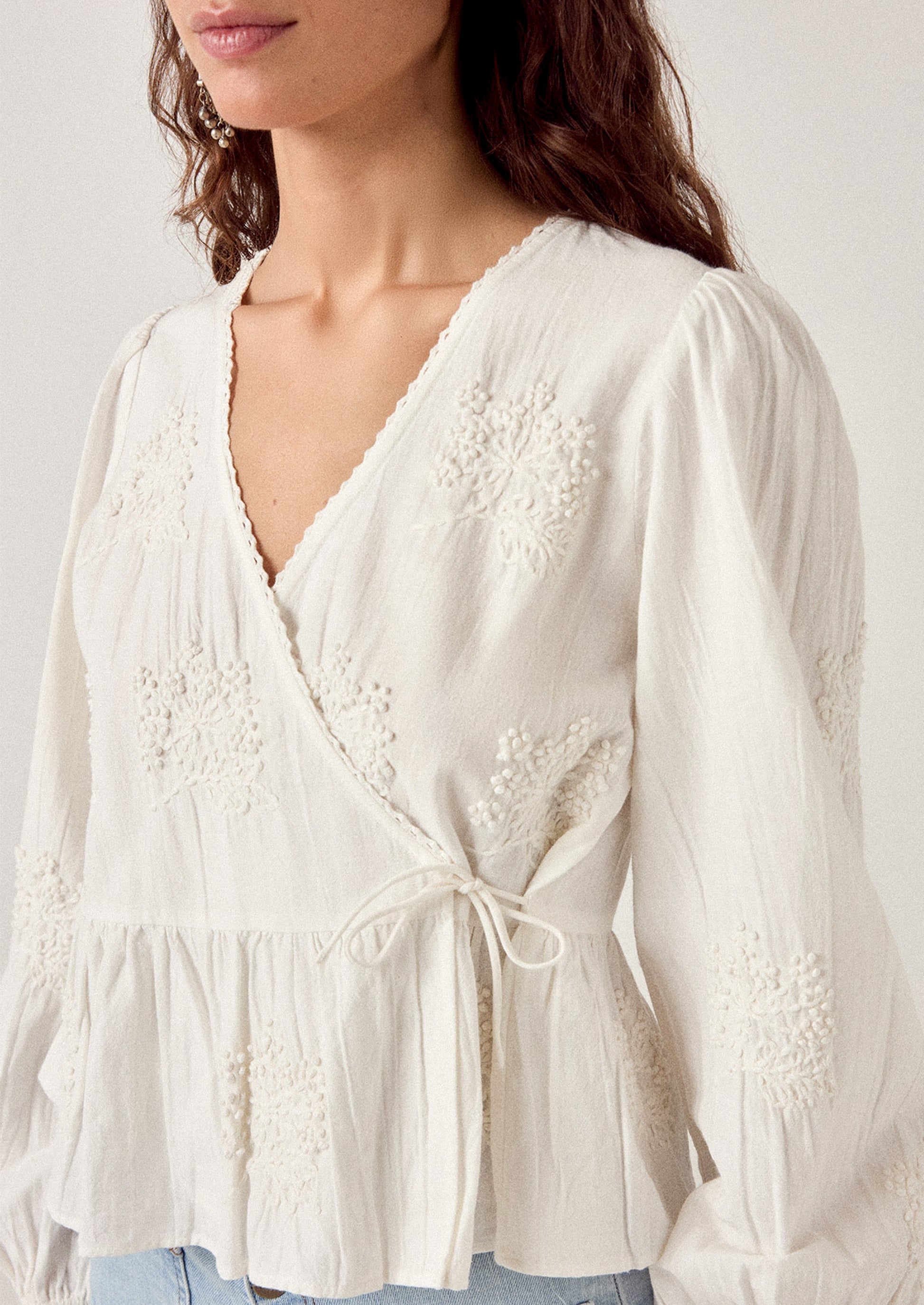 White blouse with floral embroidery on a plain background