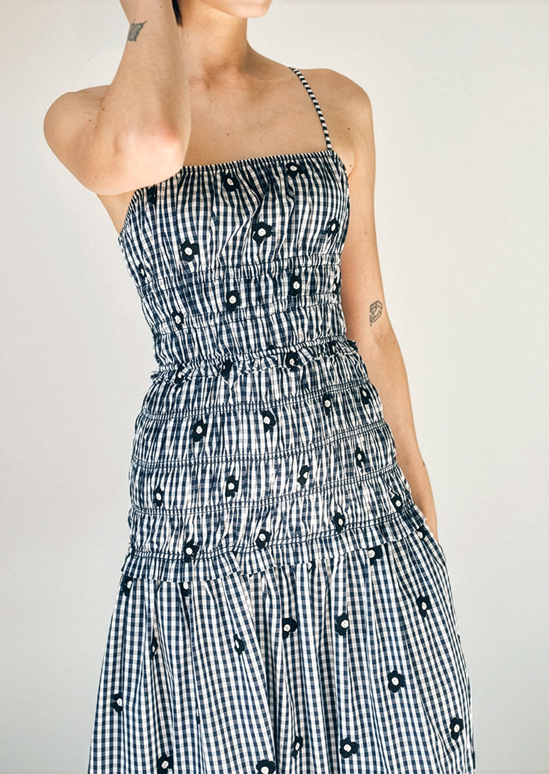 Person wearing a black and white checkered dress with a pattern of black shapes on a plain background