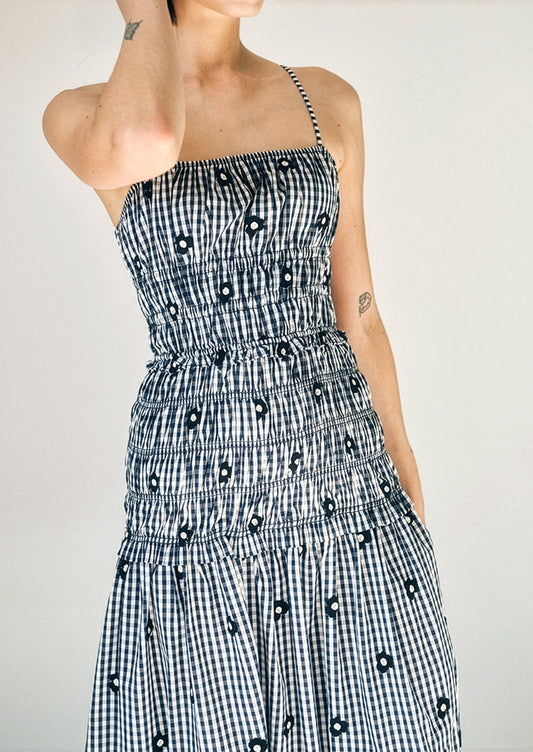 Person wearing a black and white checkered dress with a pattern of black shapes on a plain background